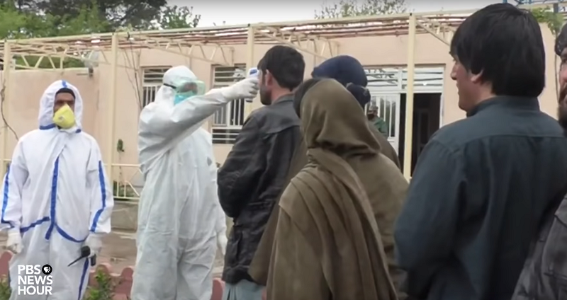 Afghan prisoners line up to have their temperature taken before being reunited with their families.